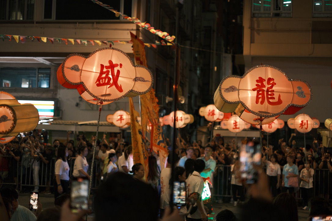 Festival lanterns moving above a dense night crowd